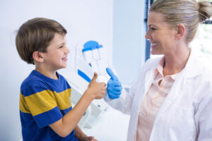 pediatric dentist giving child thumbs up